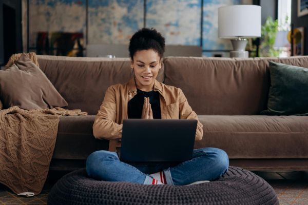 Lady sitting by couch working on laptop