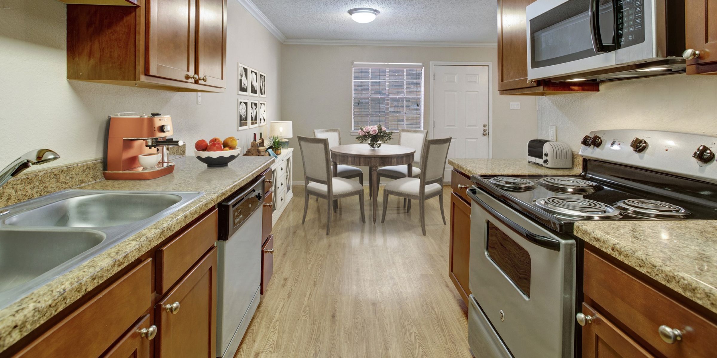 Stylish Kitchen with stainless appliances, wood plank flooring.