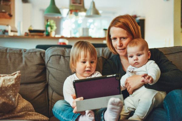 A mom with two children reading a book on the couch