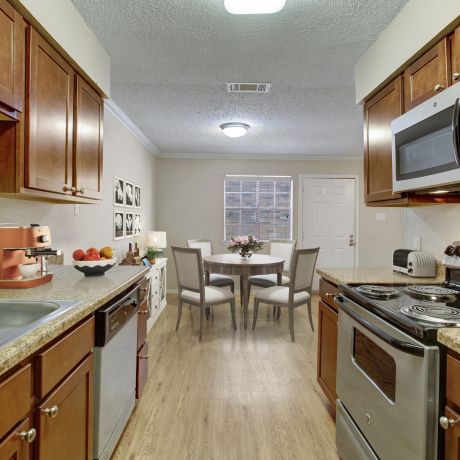 The kitchen at Autumn Chase Apartments in San Marcos, Texas, features modern appliances, wood cabinets, and a cozy dining area.